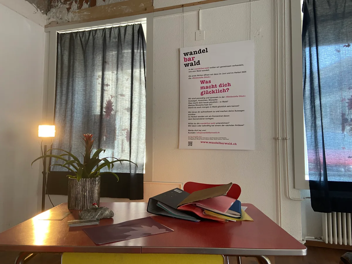 Ein Tisch in einem Raum. Dahinter brennt eine Lampe.